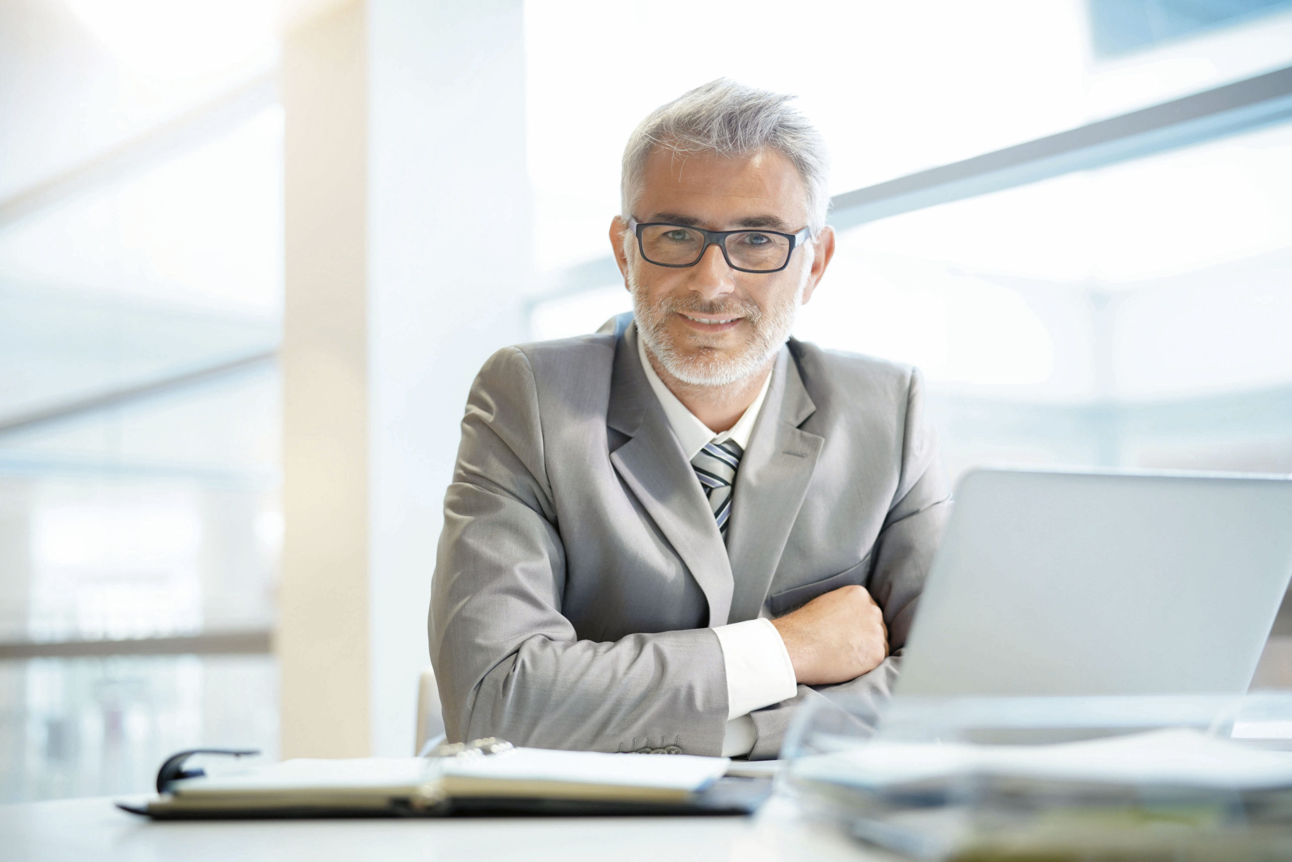 Portrait of mature businessman sitting in office looking at came